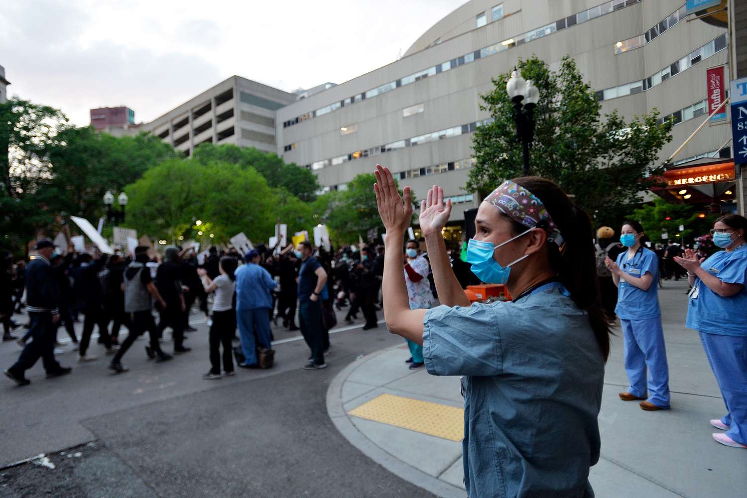 Nurses stand outside a hospital to applaud protesters marching during a demonstration over the death of George Floyd