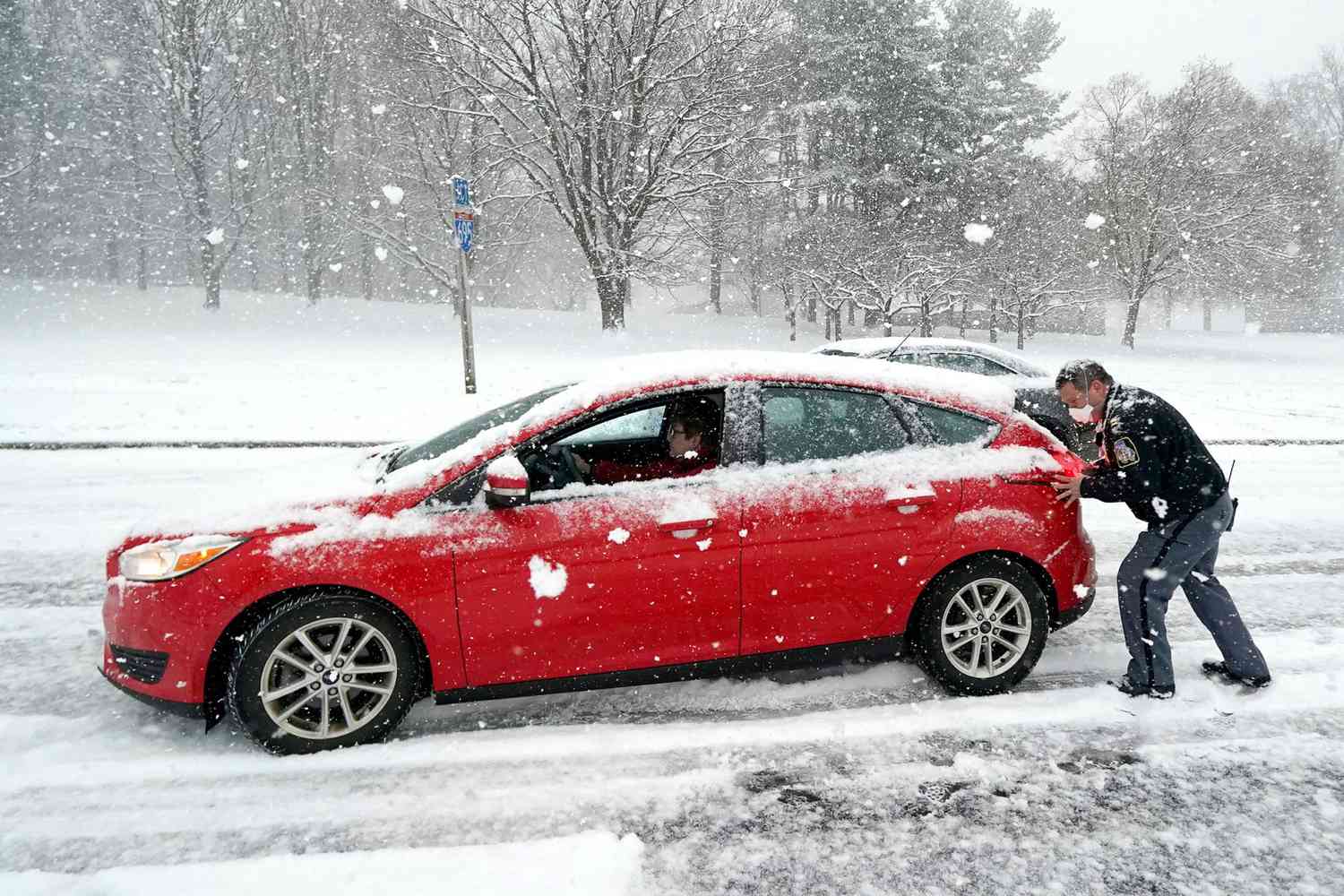Baltimore County Police Capt. Joseph Conger, right, helps a motorist push up a steep hill during a snowstorm, in Towson, Md
