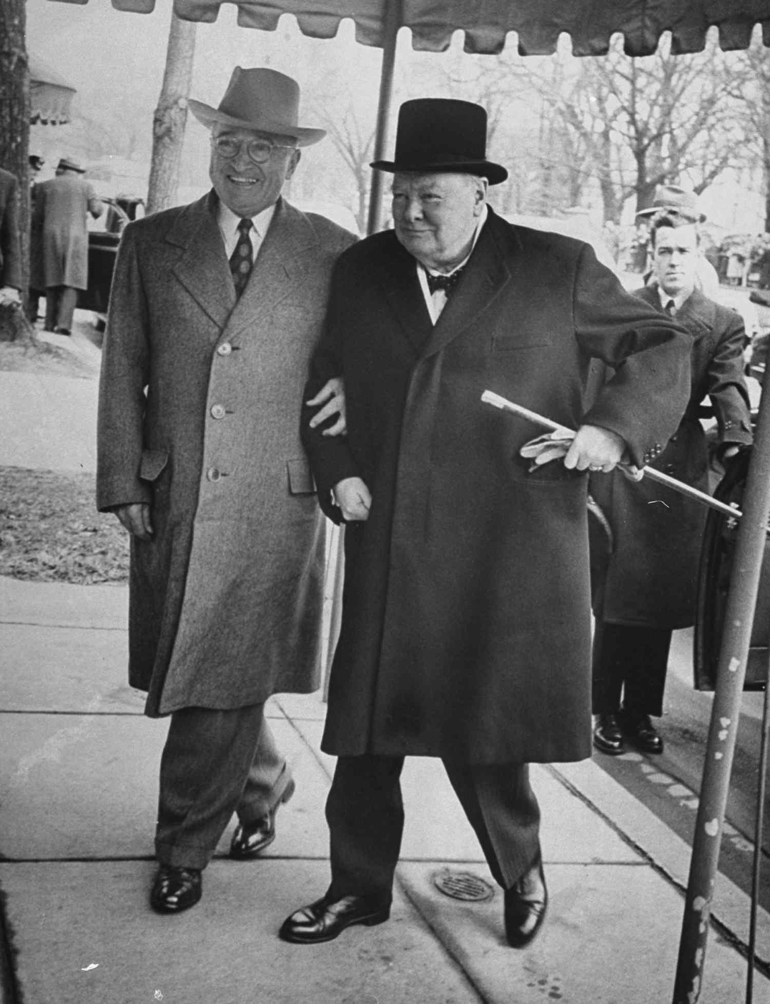 Pres. Harry Truman walking arm-in-arm w. British Prime Minister Winston Churchill as he arrives at Blair House for his visit to discuss foreign affairs