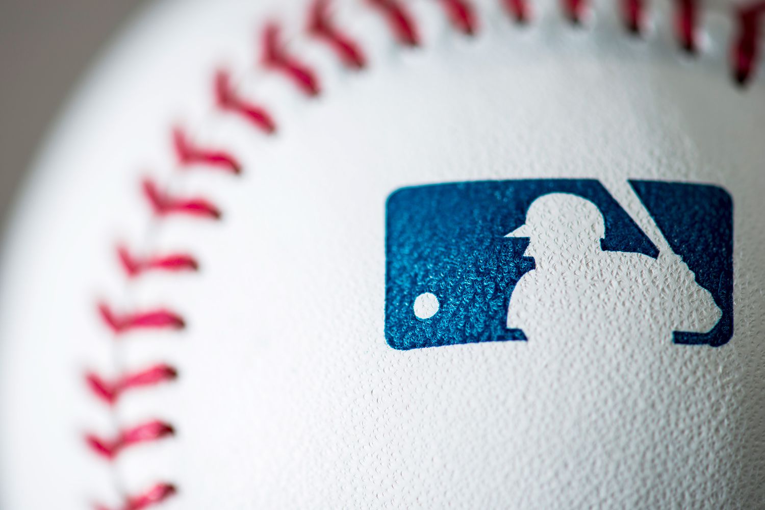 A detail view of the Major League Baseball logo on a baseball
