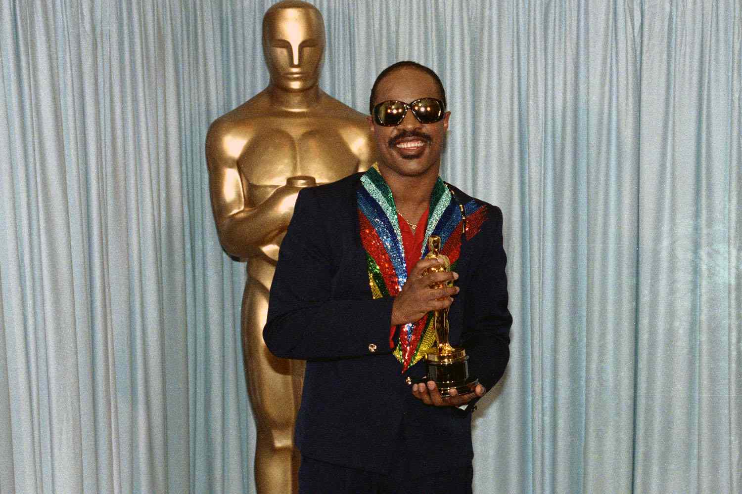 Stevie Wonder who began learning the piano at the age of seven holds his Oscar award for the category of Best Song.