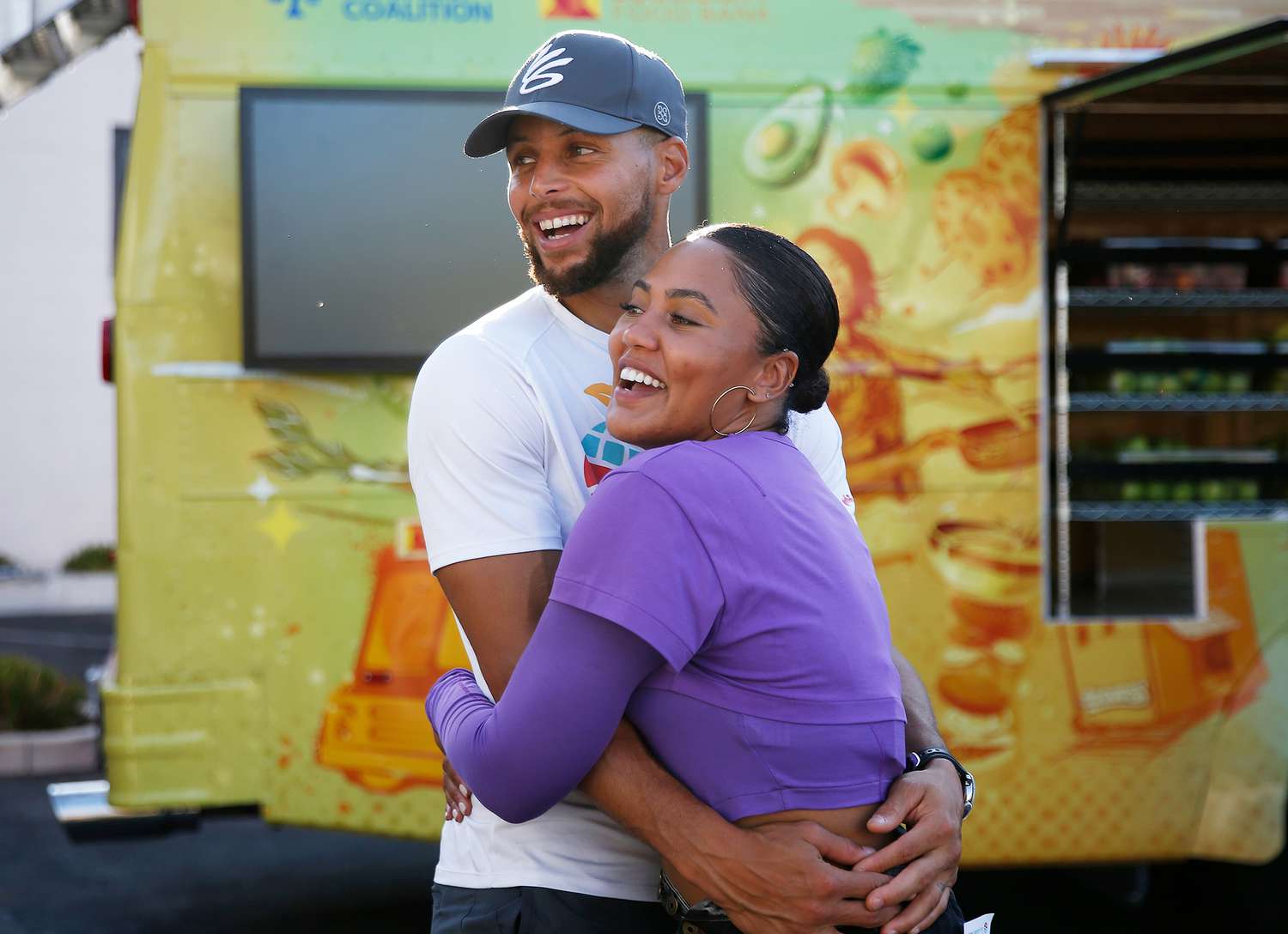 Stephen and Ayesha Curry hug during the unveiling of the Eat. Learn. Play. bus at the East Oakland Youth Development Center in Oakland, Calif