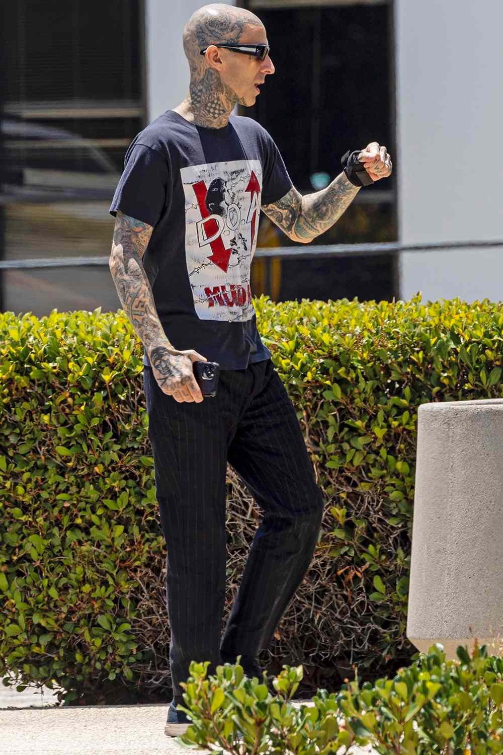 *PREMIUM-EXCLUSIVE* Calabasas, CA - Travis Barker is back on his feet following a health scare that put the Blink-182 drummer in the hospital. Trav is spotted arriving at his Calabasas recording studio wearing his usual dark clothing as he fist bumps a buddy on his way inside. Pictured: Travis Barker BACKGRID USA 5 JULY 2022 USA: +1 310 798 9111 / usasales@backgrid.com UK: +44 208 344 2007 / uksales@backgrid.com *UK Clients - Pictures Containing Children Please Pixelate Face Prior To Publication*