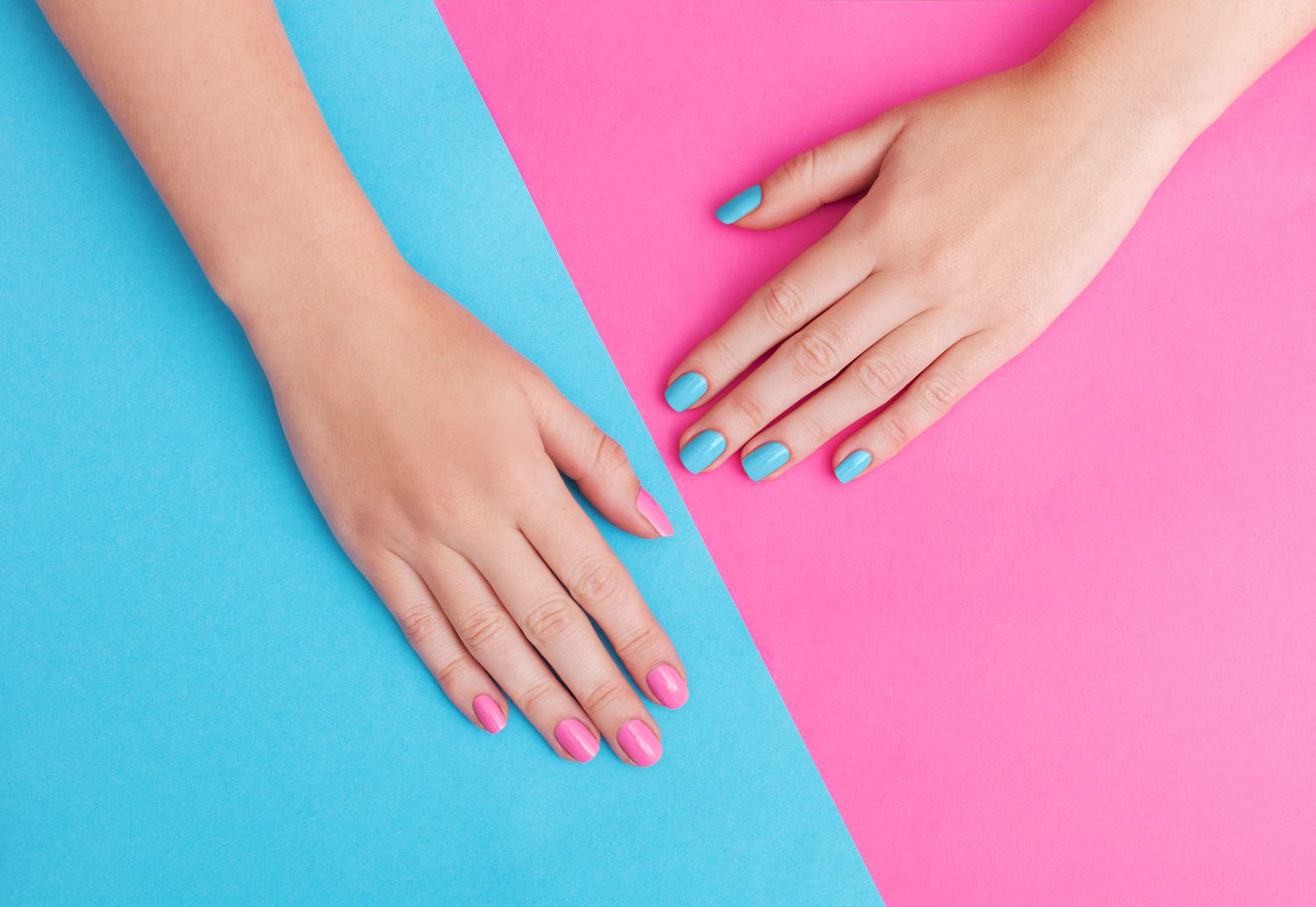 Closeup of hands of a young woman with manicure on nails against pink background