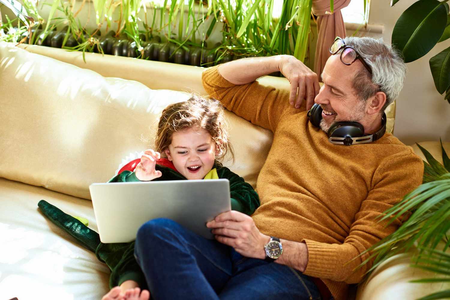Mature father watching online tv with daughter in dinosaur costume