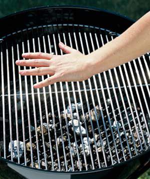 Hand on barbeque grill testing for heat