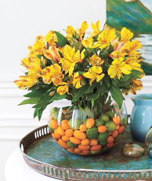 Citrus fruit and Peruvian lillies in a glass fish bowl flower arrangement