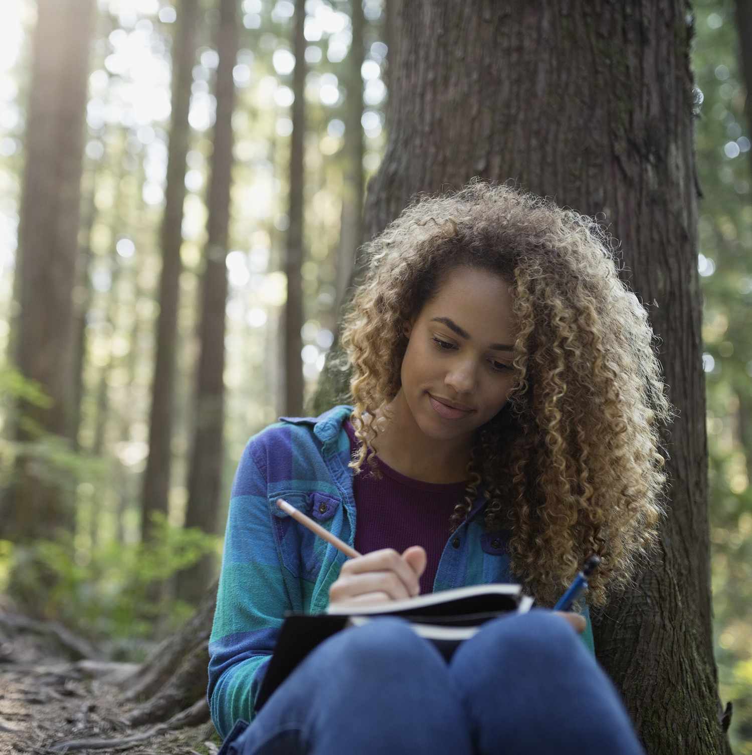 Woman writing in journal in woods