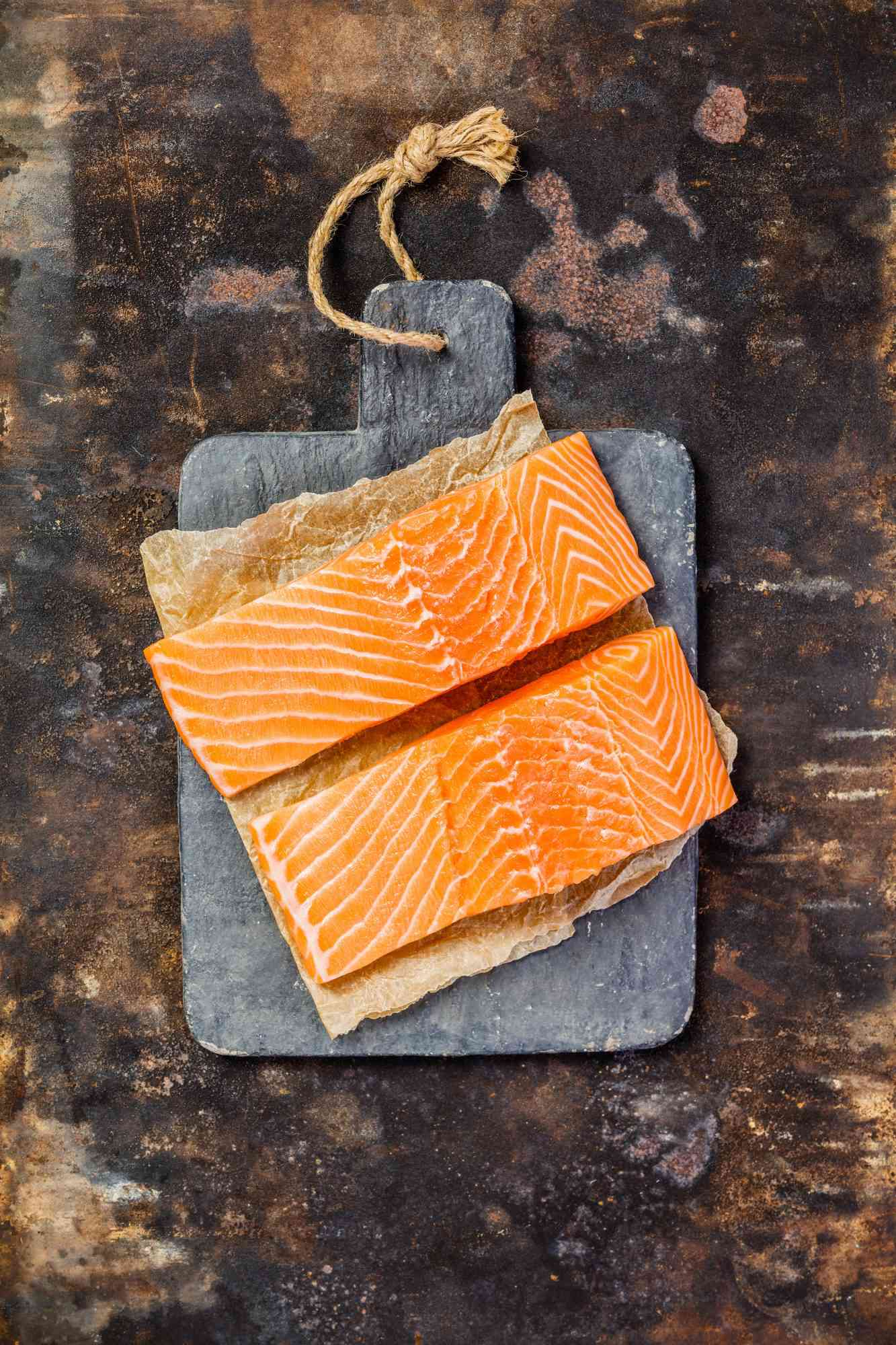 two pieces of raw salmon on a cutting board