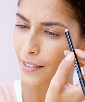 Woman defining eyebrows with eye pencil