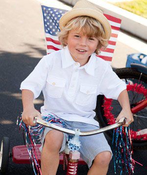Young boy on tricycle with American flag and streamers