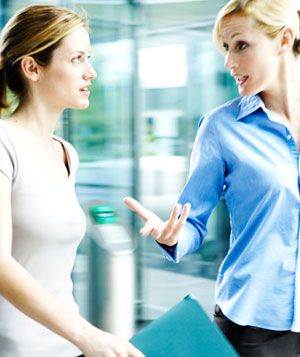 Two businesswomen talking, walking through office building