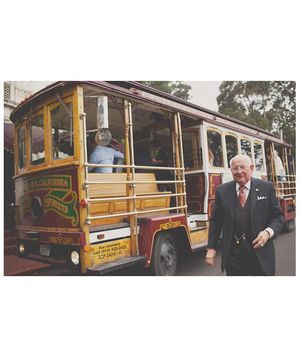 Old man in a suit standing outside of a street trolley