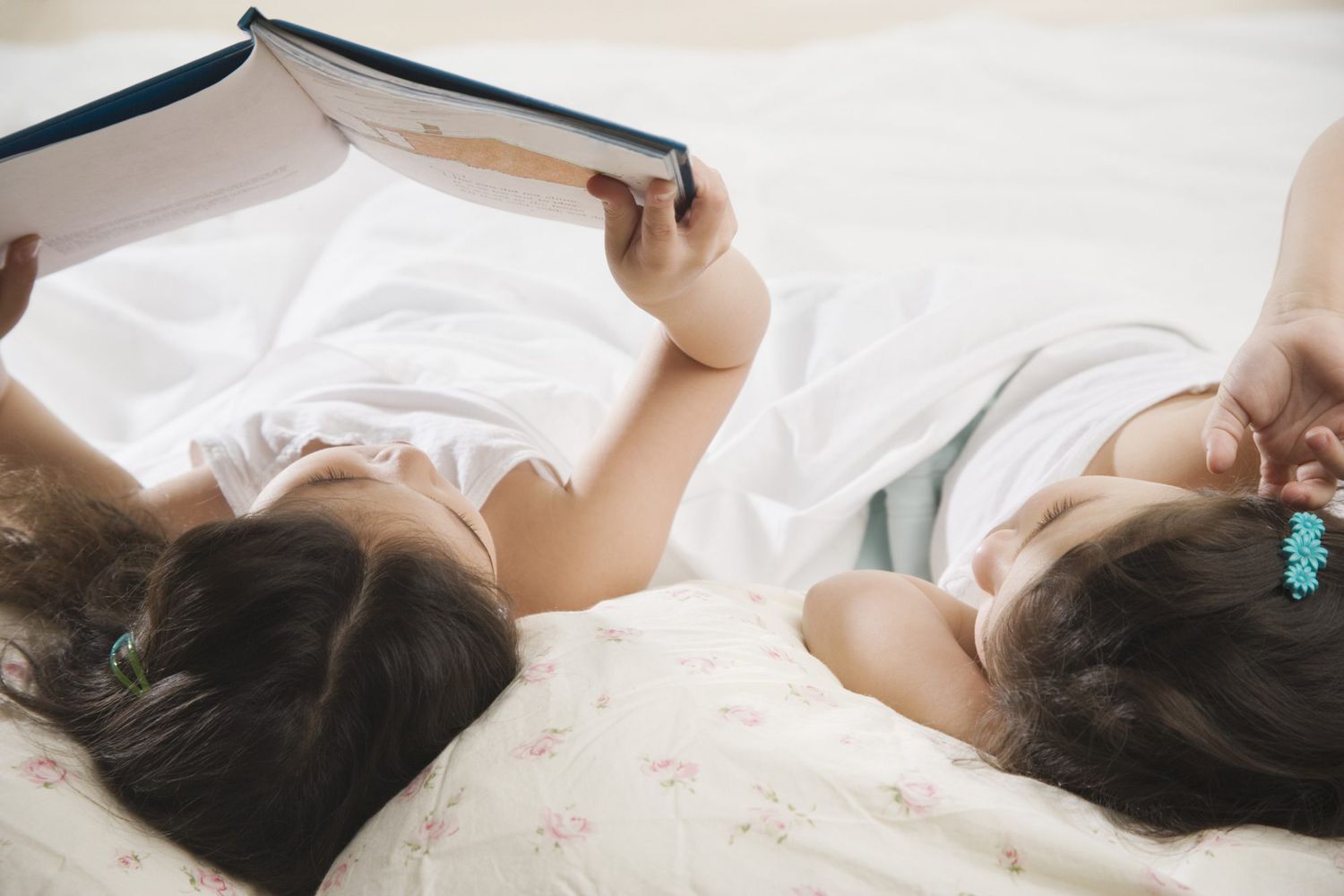 Two children reading a book in bed