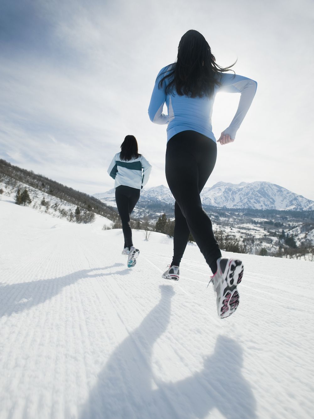 women running through snow in mountains