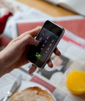 Hand using smartphone at breakfast table