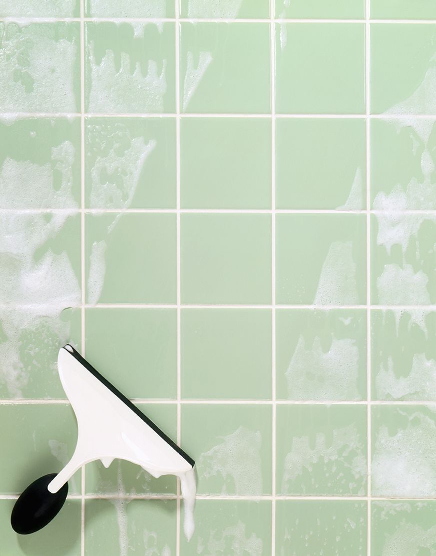 Window squeegee cleaning soap suds on green tile
