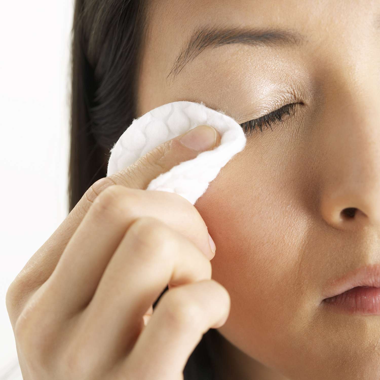 Woman wiping eye with cotton pad