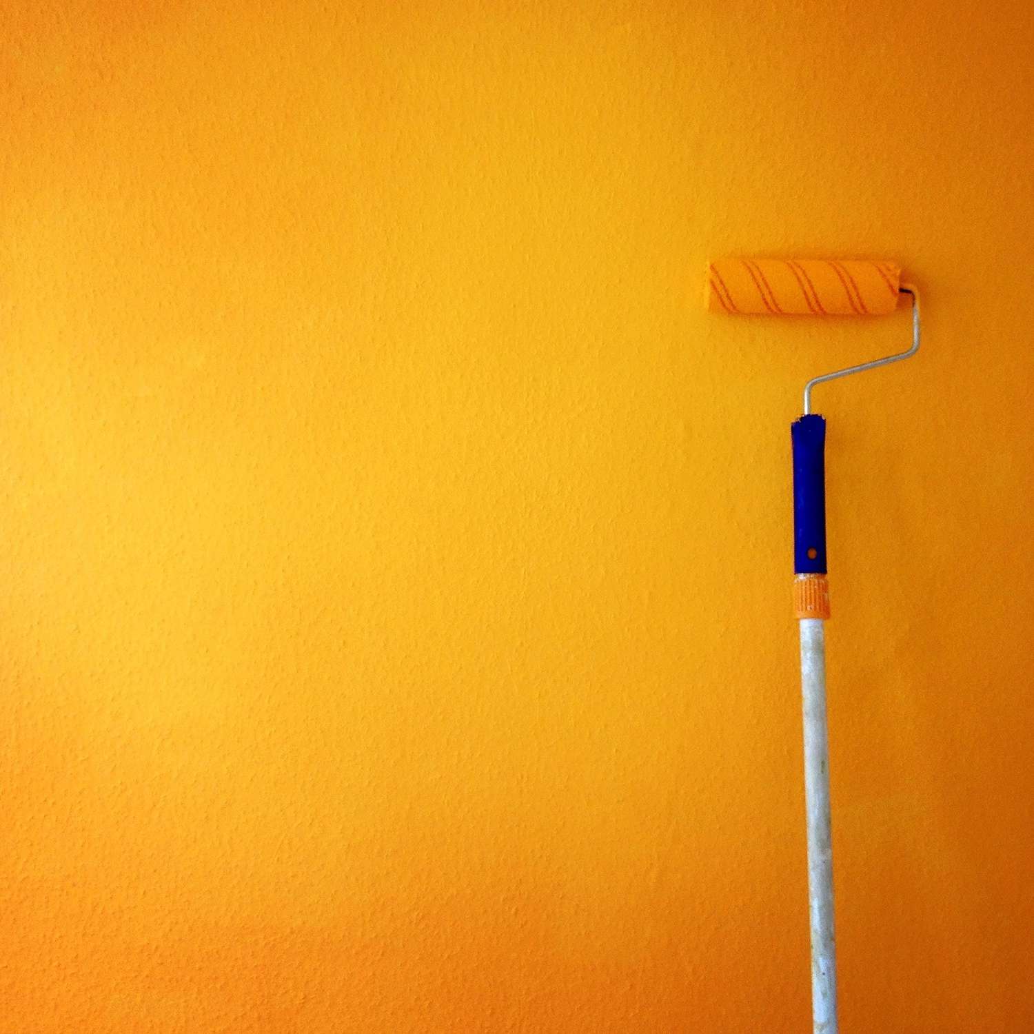 Paint roller leaning on yellow-orange accent wall