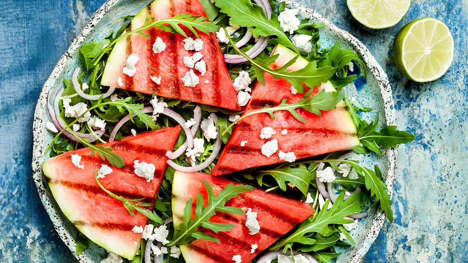 grilled food ideas: Fresh summer grilled watermelon salad with feta cheese, arugula, onions on blue background