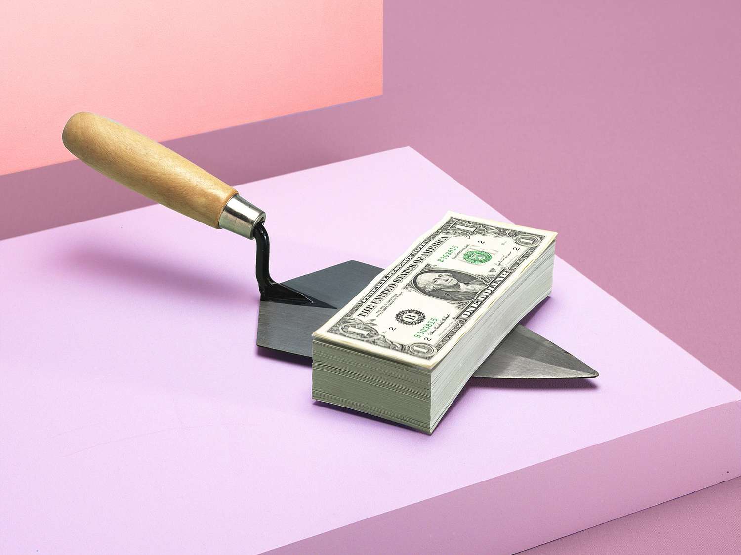 money on a spade with a pink background