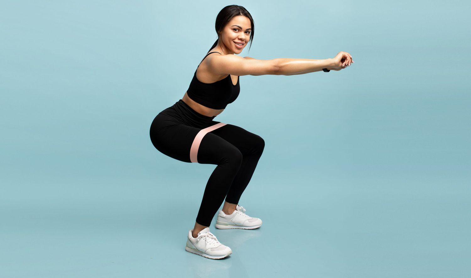 Strength workout concept. woman doing squats with fitness resistance band over blue background
