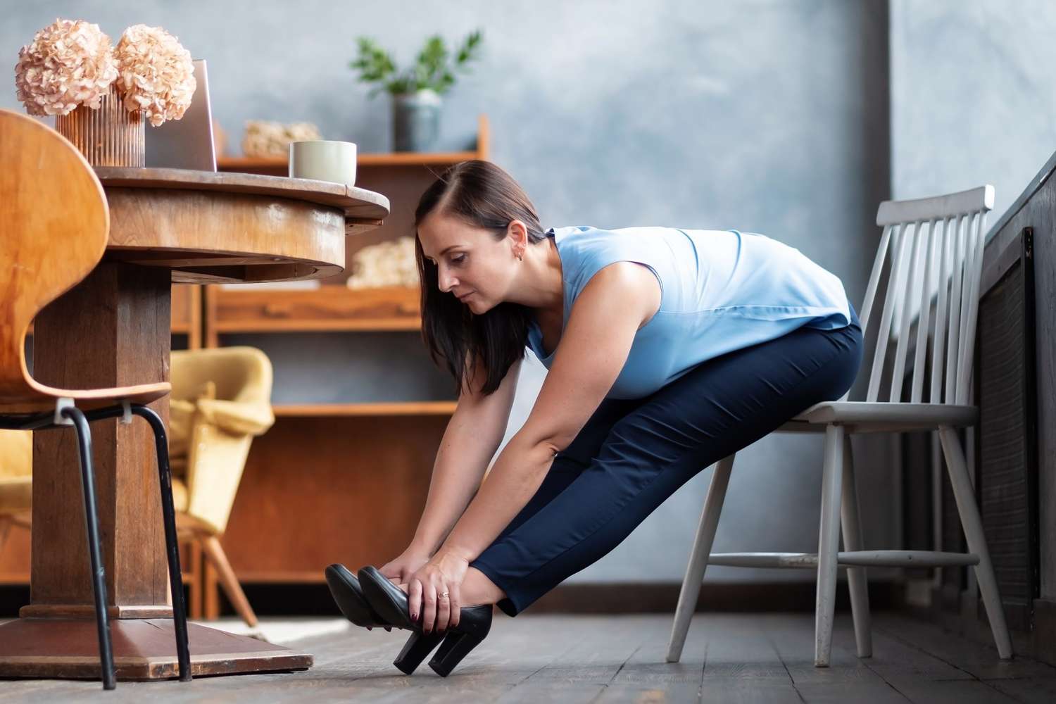 Chair Yoga Poses and Stretching: woman sitting in a chair and stretching to touch her toes