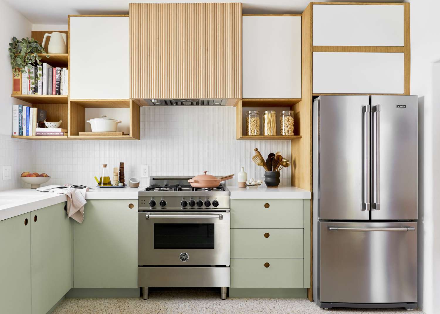 Кухня чистого дизайна со светло-зелеными нижними шкафами и тамбурной вытяжкой