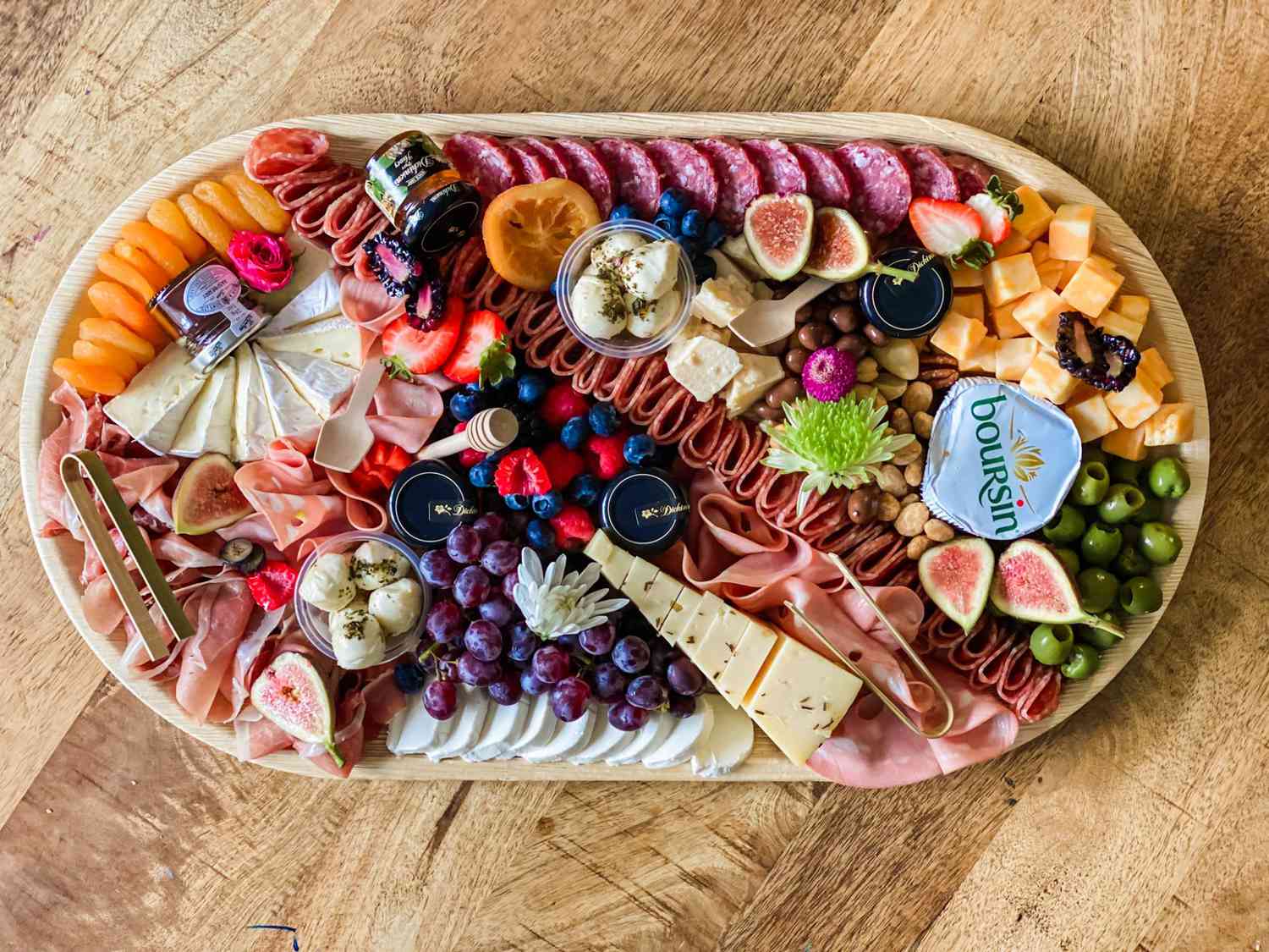 charcuterie board by French Boards and Bites NY with meats, cheese, olives, grapes, and berries.