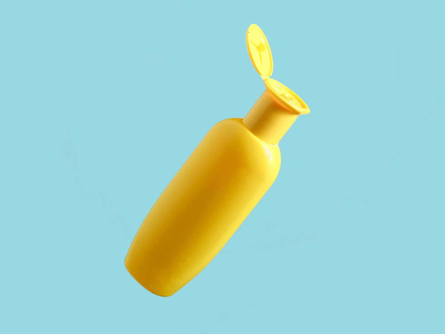 Yellow bottle of shower gel on blue background. Minimalism, conceptual photo, photo with shadow.