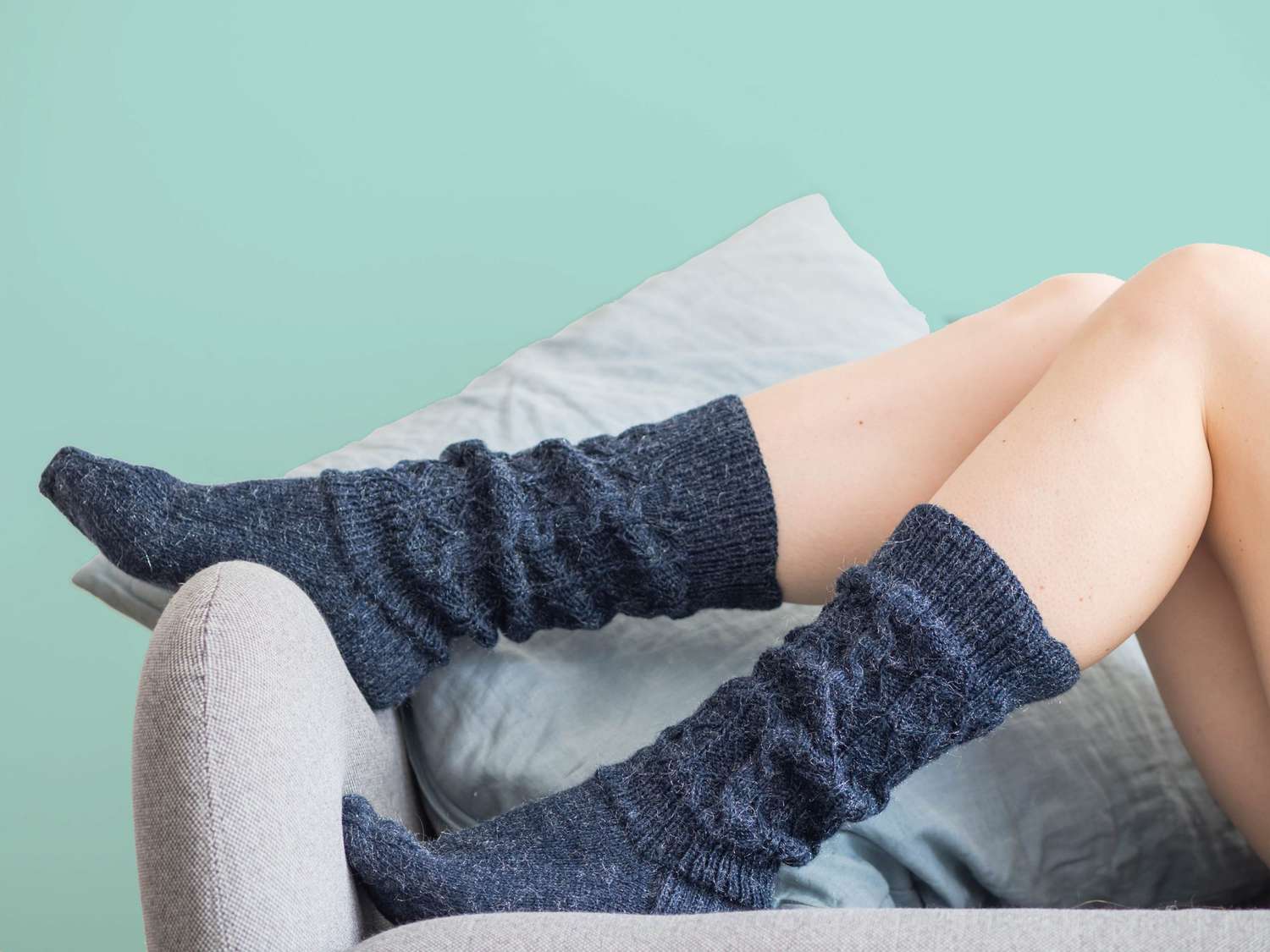 Why are my feet always cold? Low Section Of Woman In Socks Sitting On Sofa At Home