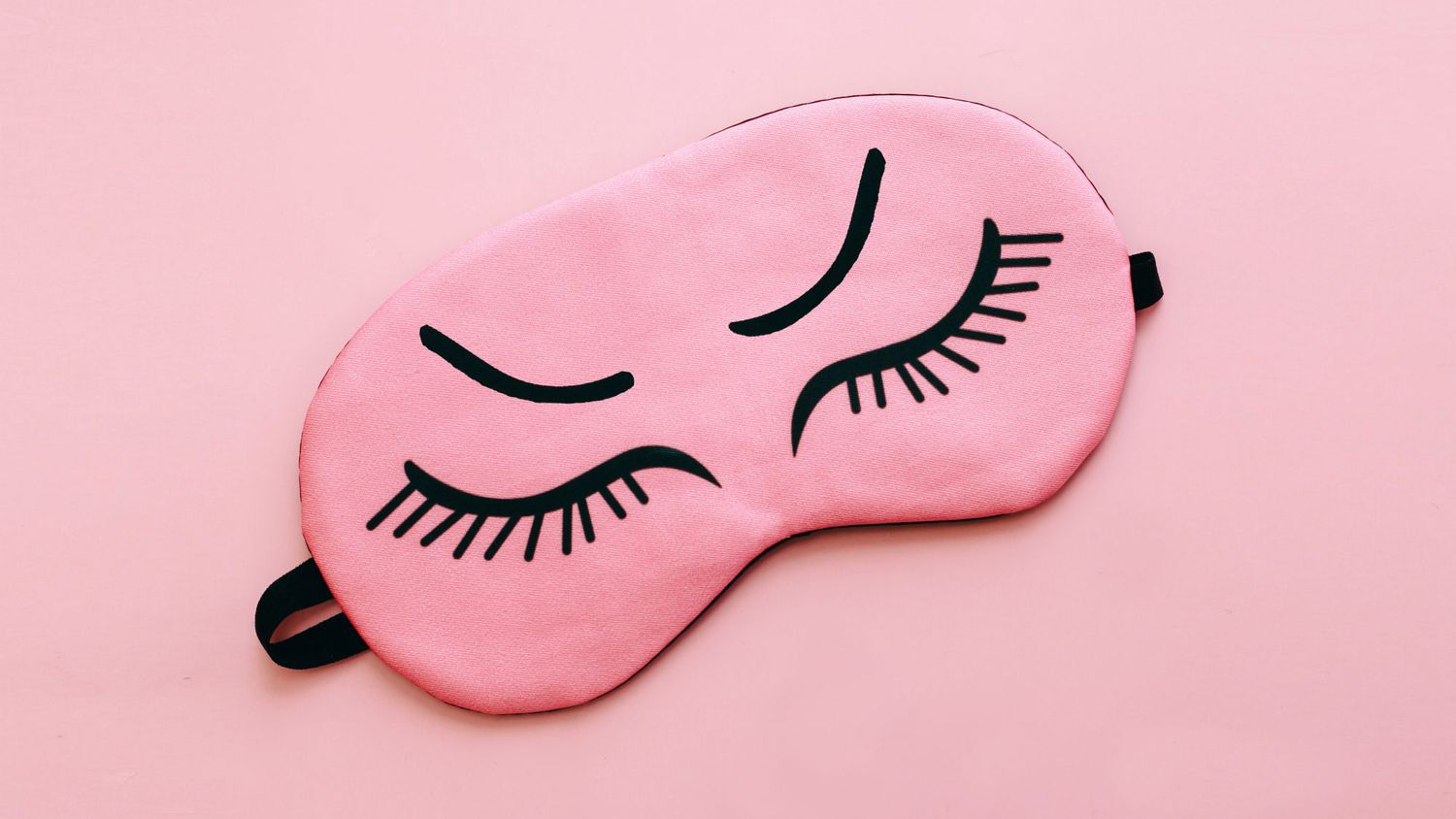 Pink sleep mask, vitamins capsules over pink background. Concept of sleep, health care and daily routine.