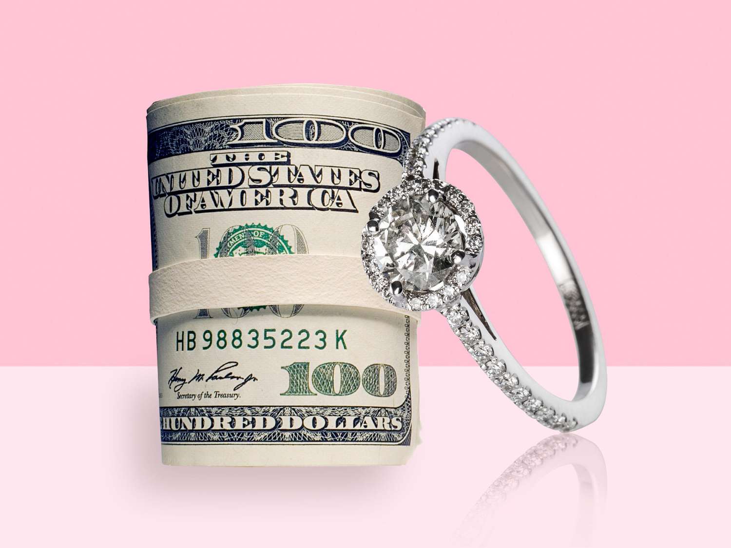 engagement ring next to a roll of $100 bills