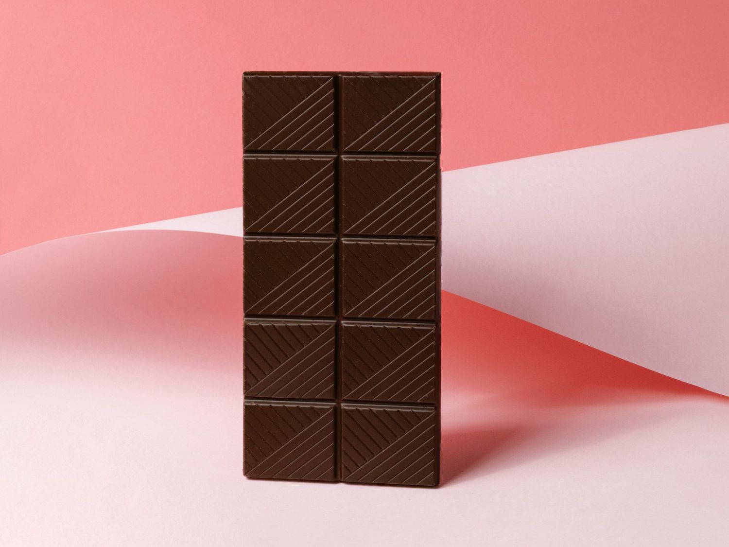whole bar of dark chocolate on pink abstract background