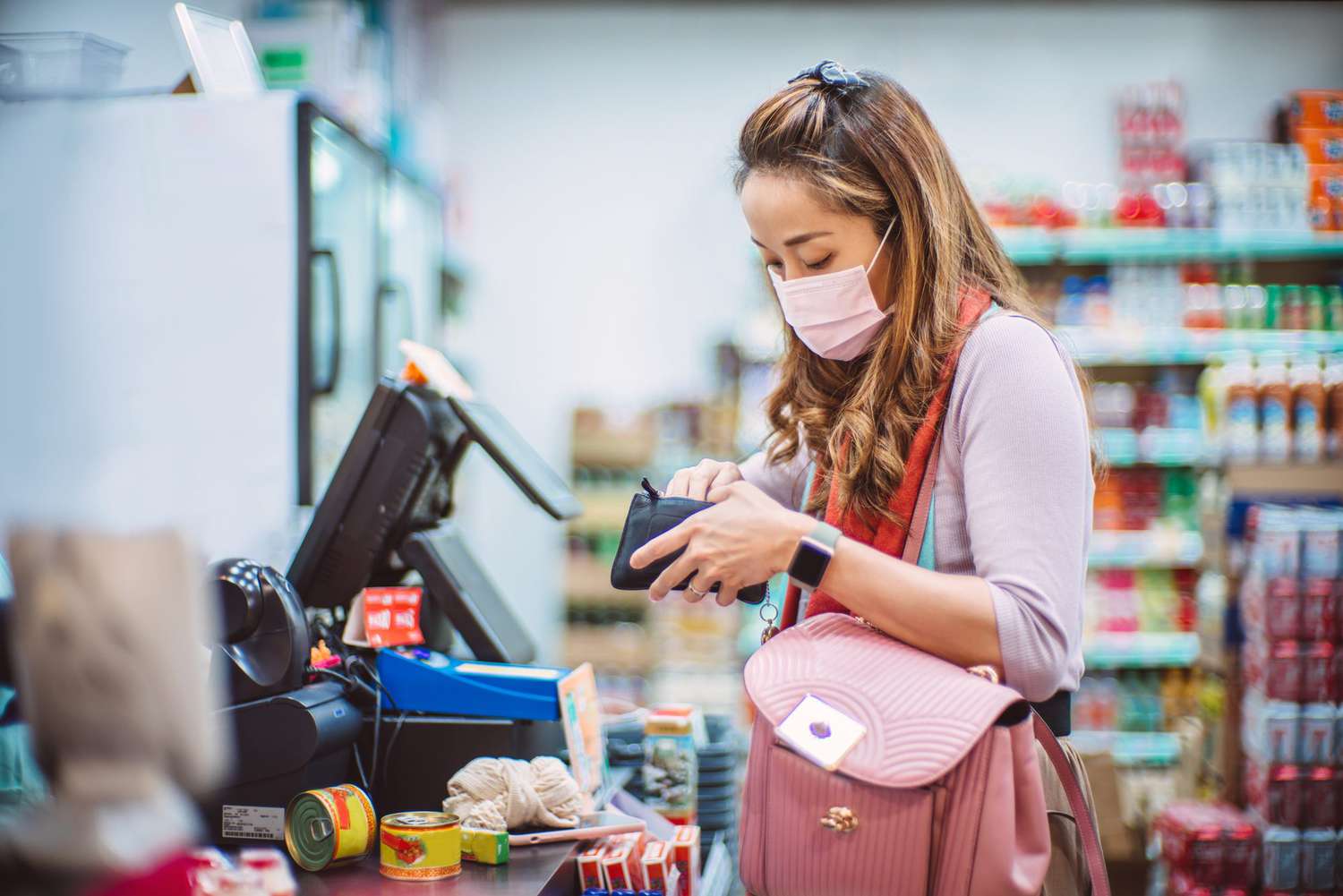 woman with medical face mask making payment in groceries store