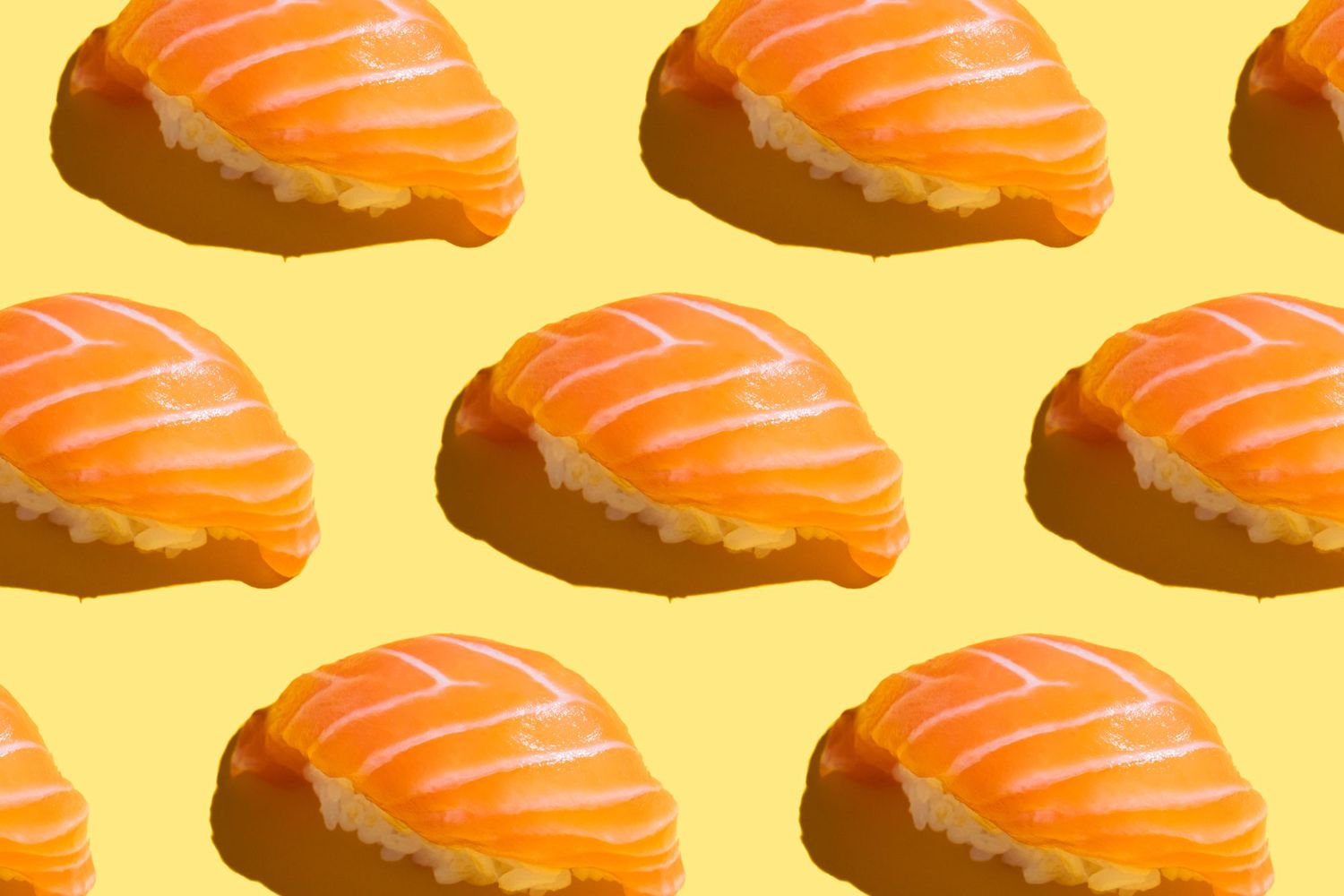 Japanese food sushi pattern with salmon with hard shadow on bright yellow background.