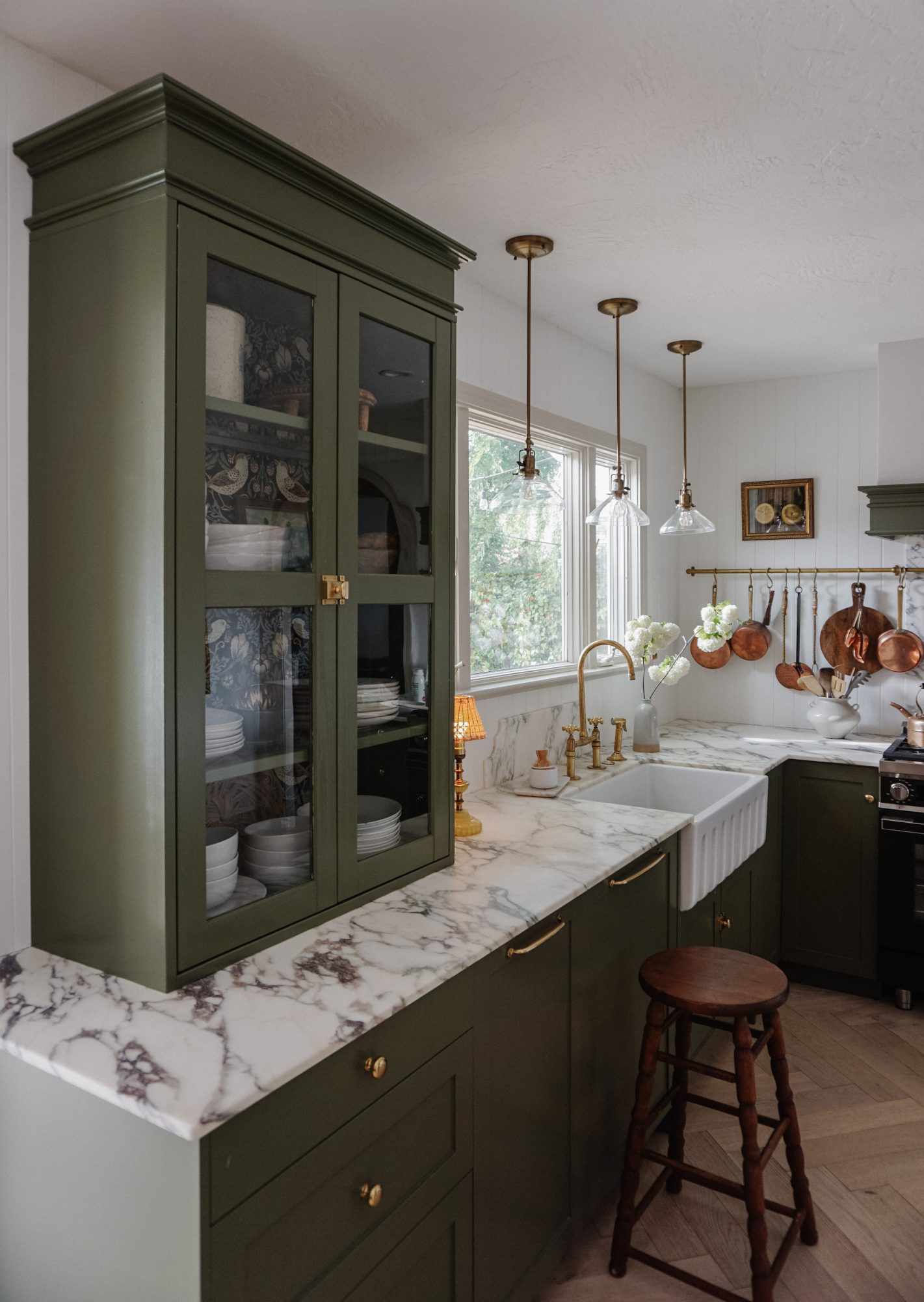 Cottagecore kitchen with sage green cabinets and hanging pendant lamps over farmhouse sink