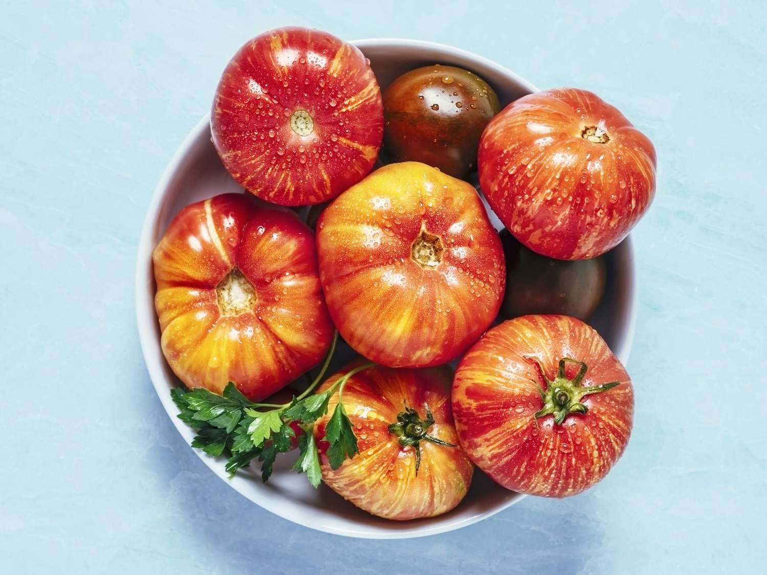 Bowl of heirloom tomatoes on blue background