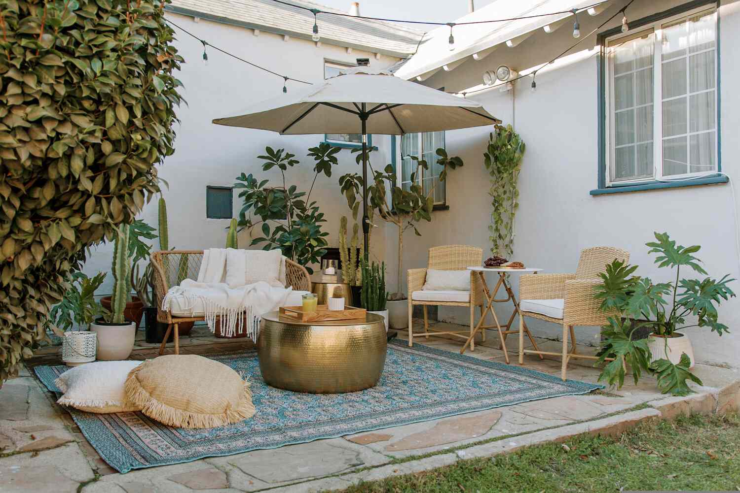 outdoor patio with large umbrella, woven chairs, and a teal outdoor rug