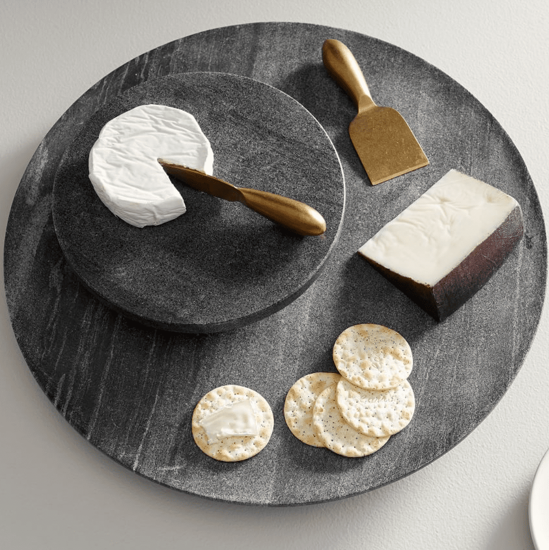 black marble lazy susan with cheese and crackers on it