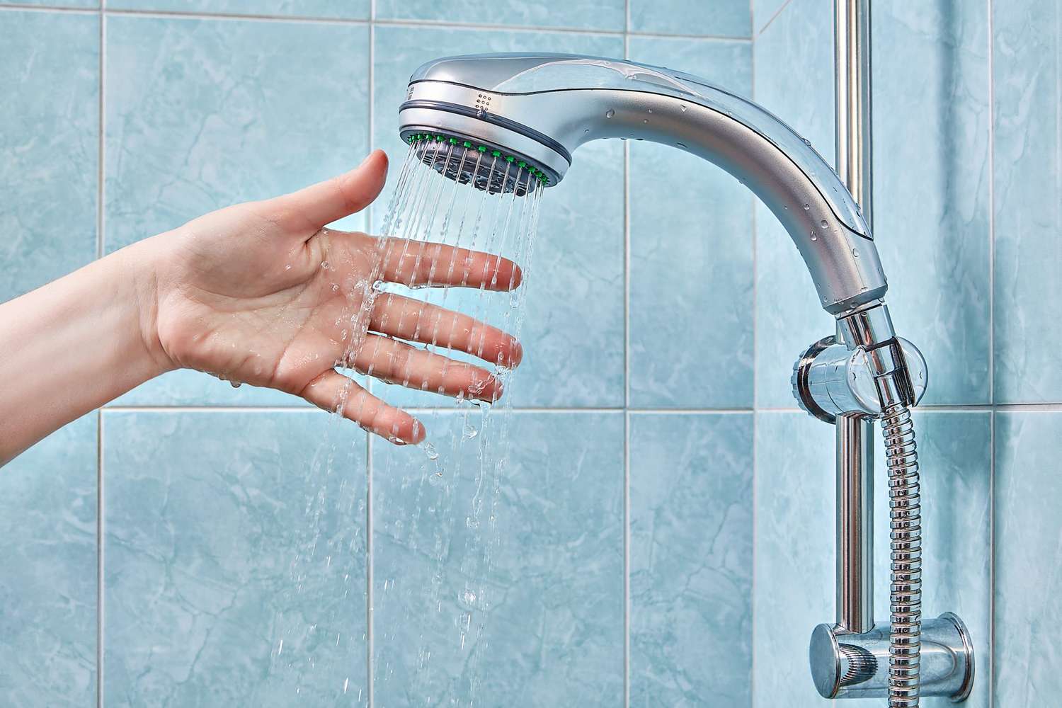 Woman's hand under chrome shower head