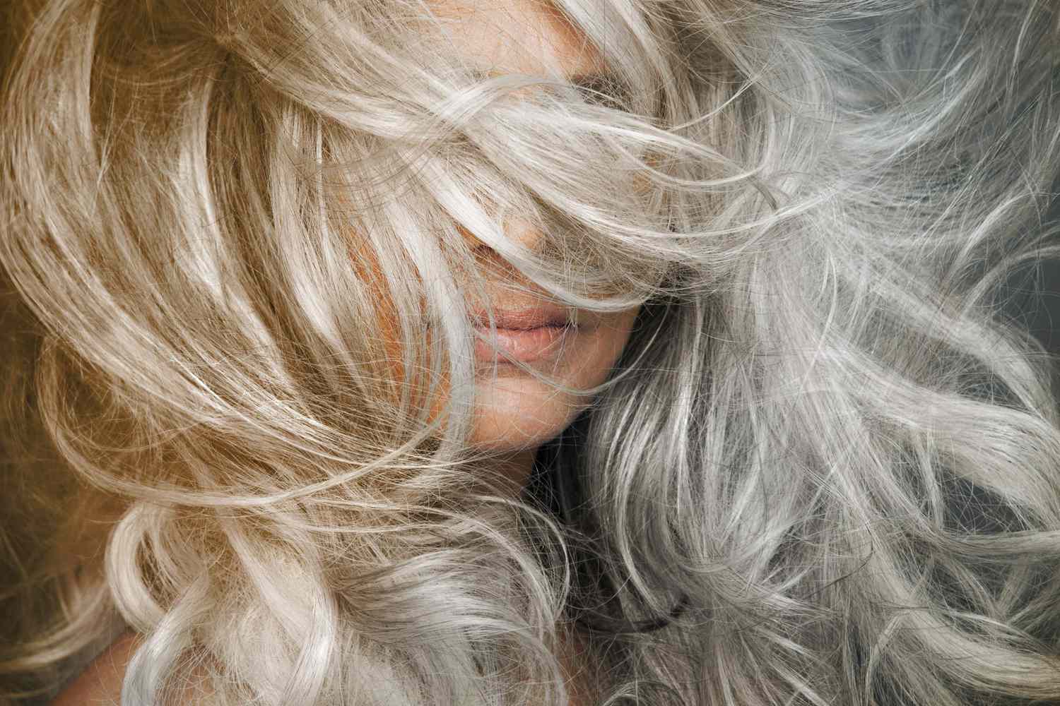 Woman with grey hair blowing across her face.