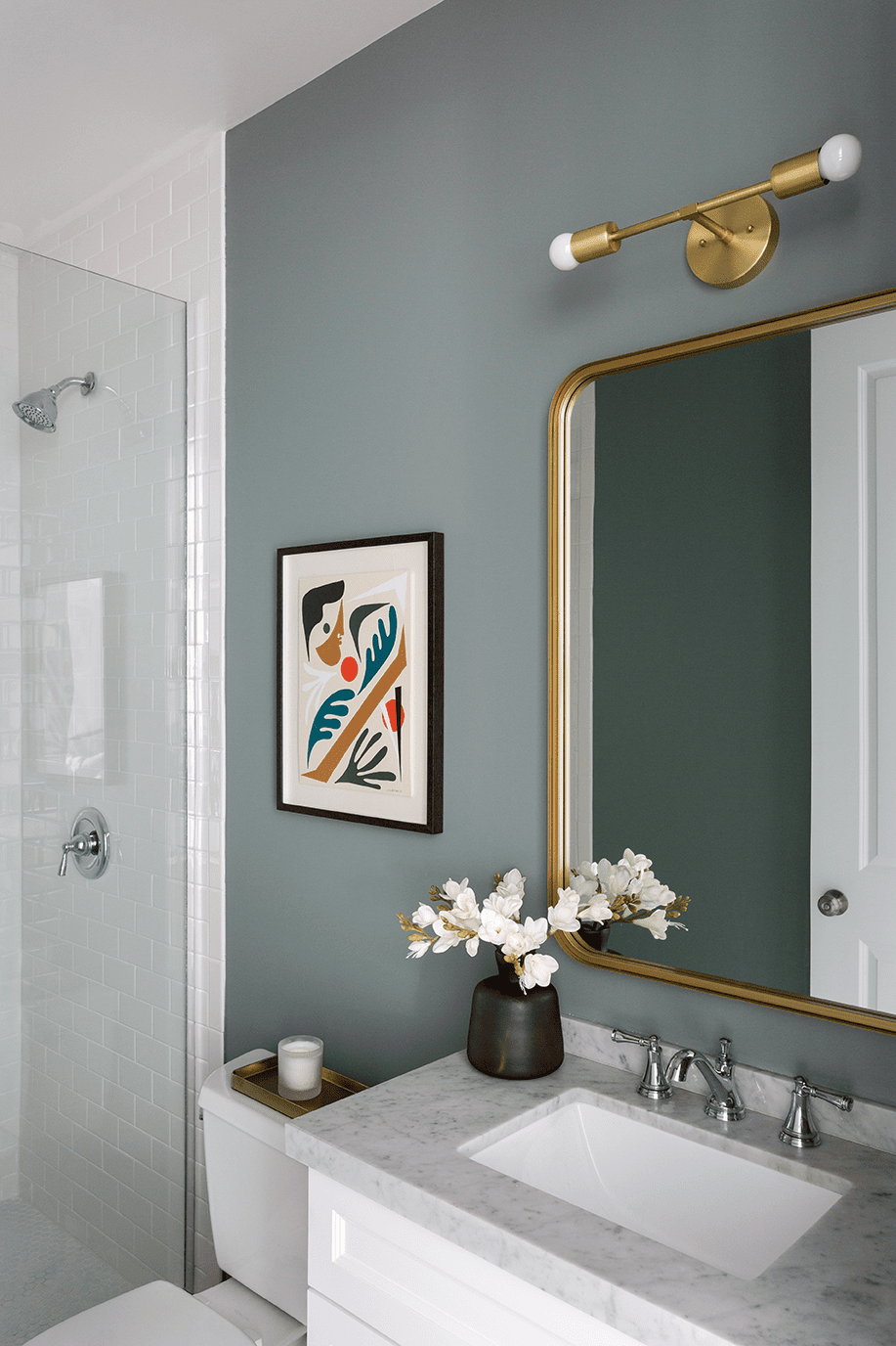 Bathroom with matte green sage wall paint and green light fixture and mirror