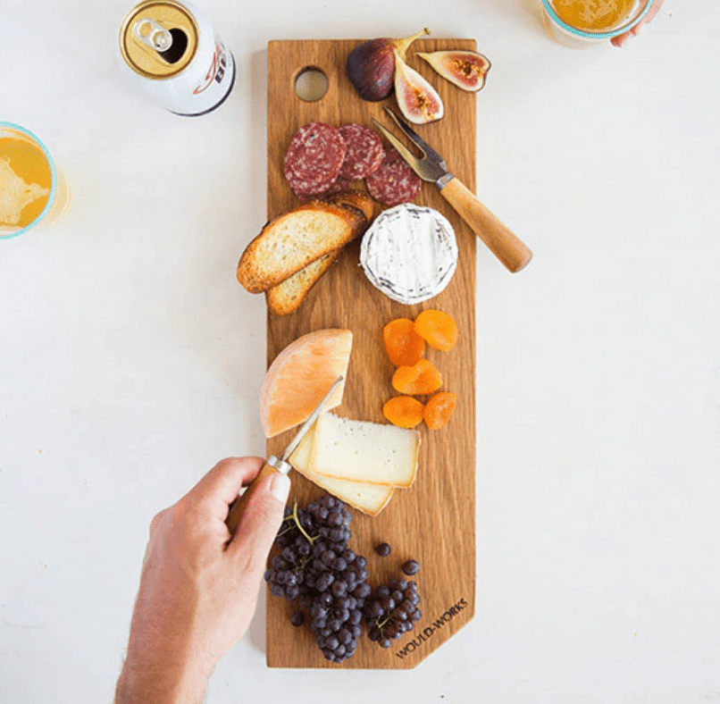 Wooden charcuterie board with cheese, fruit, and meat displayed on it