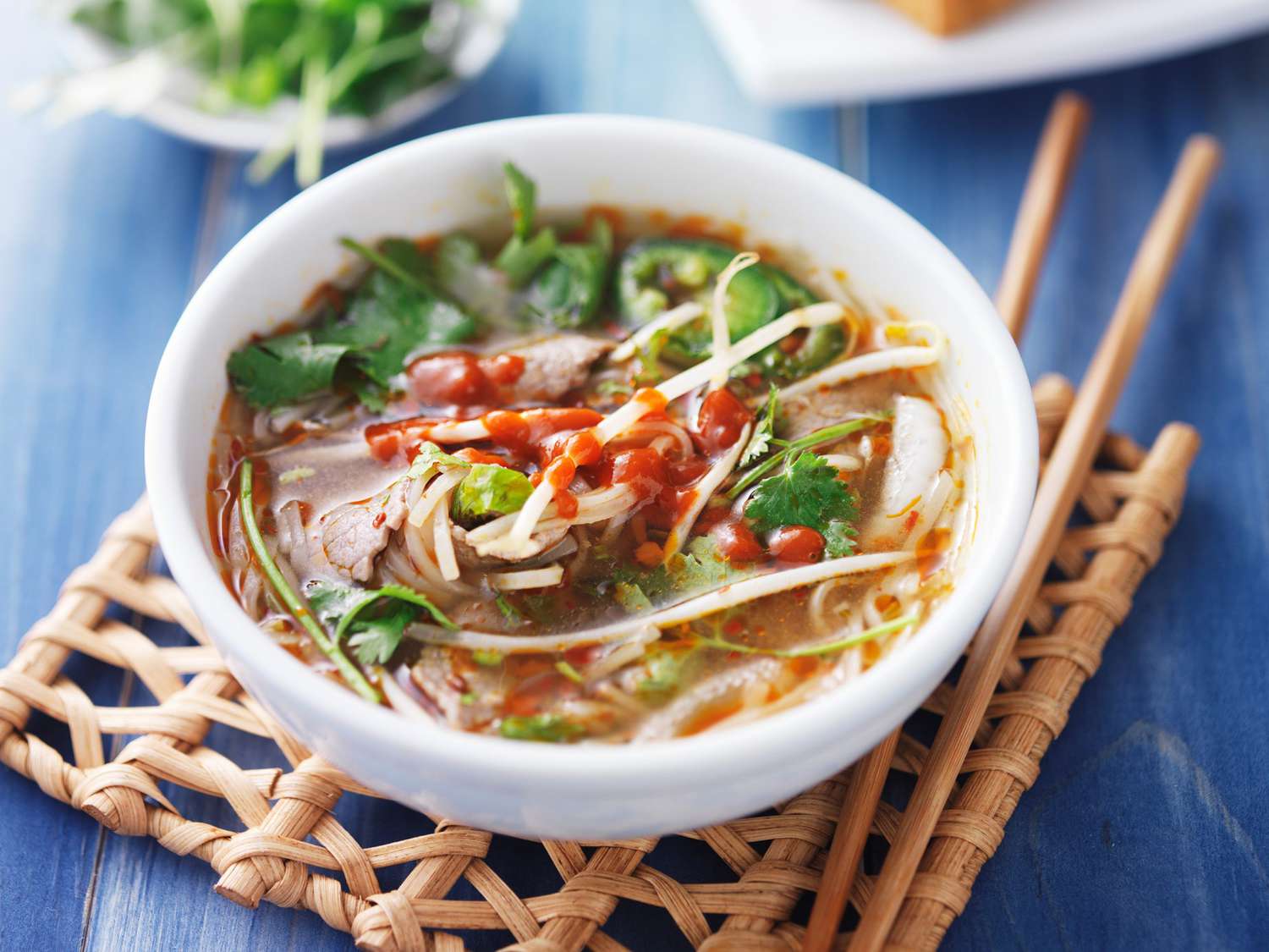 A bowl of noodle soup with sriracha on top