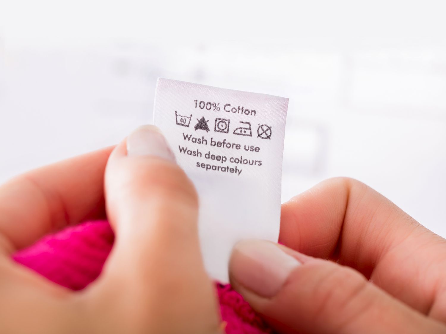 hands holding a laundry tag on pink sweater