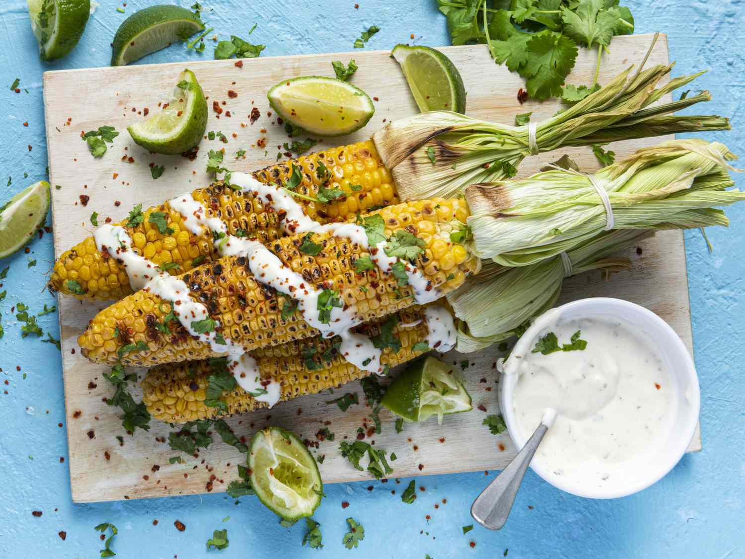 Grilled BBQ Corn Cob with Herbs, Lime and Garlic Sauce. Mexican Street Food or Summer Garden Party Snack