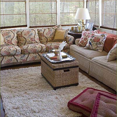 Couches are against the windows of the living room while a white, plush carpet rug is laid in the center of the room--which creates more space for children to play in the living room.