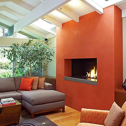 A vibrant tomato bisque-hued plaster added to this fireplace remodel turned the hearth into a modern showpiece in this living room.
