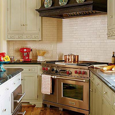stainless steel gas stove range in a kitchen with creamy, subway tiles as the backsplash behind the stove and light, tan kitchen cabinetry to the left and right of it